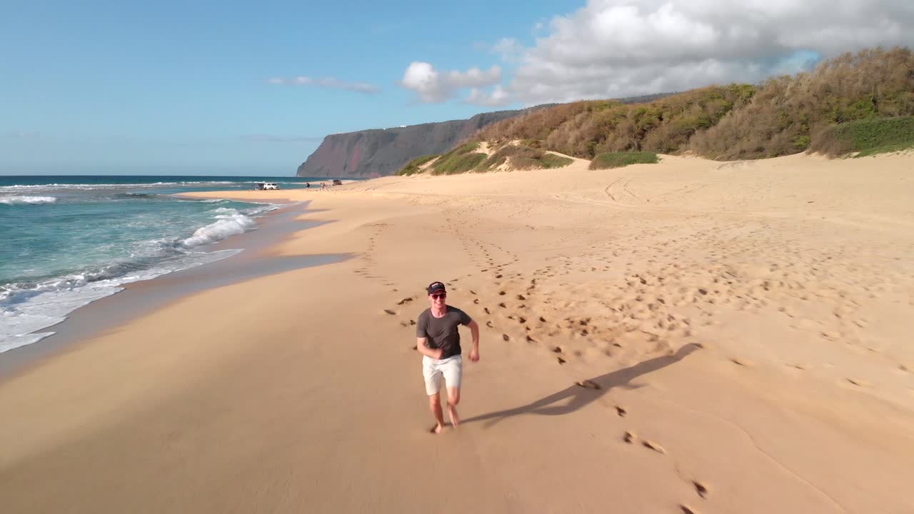Version Two. Aerial Tracking Shot of Young Man Running on Golden Secluded Beach in Hawaii.