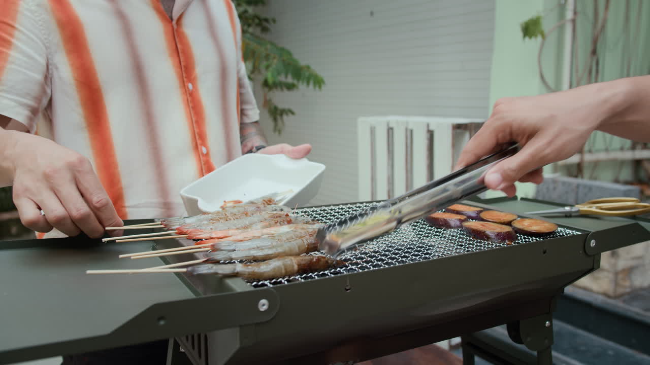 Unrecognizable Friends Cooking Shrimps on Grill Outdoors