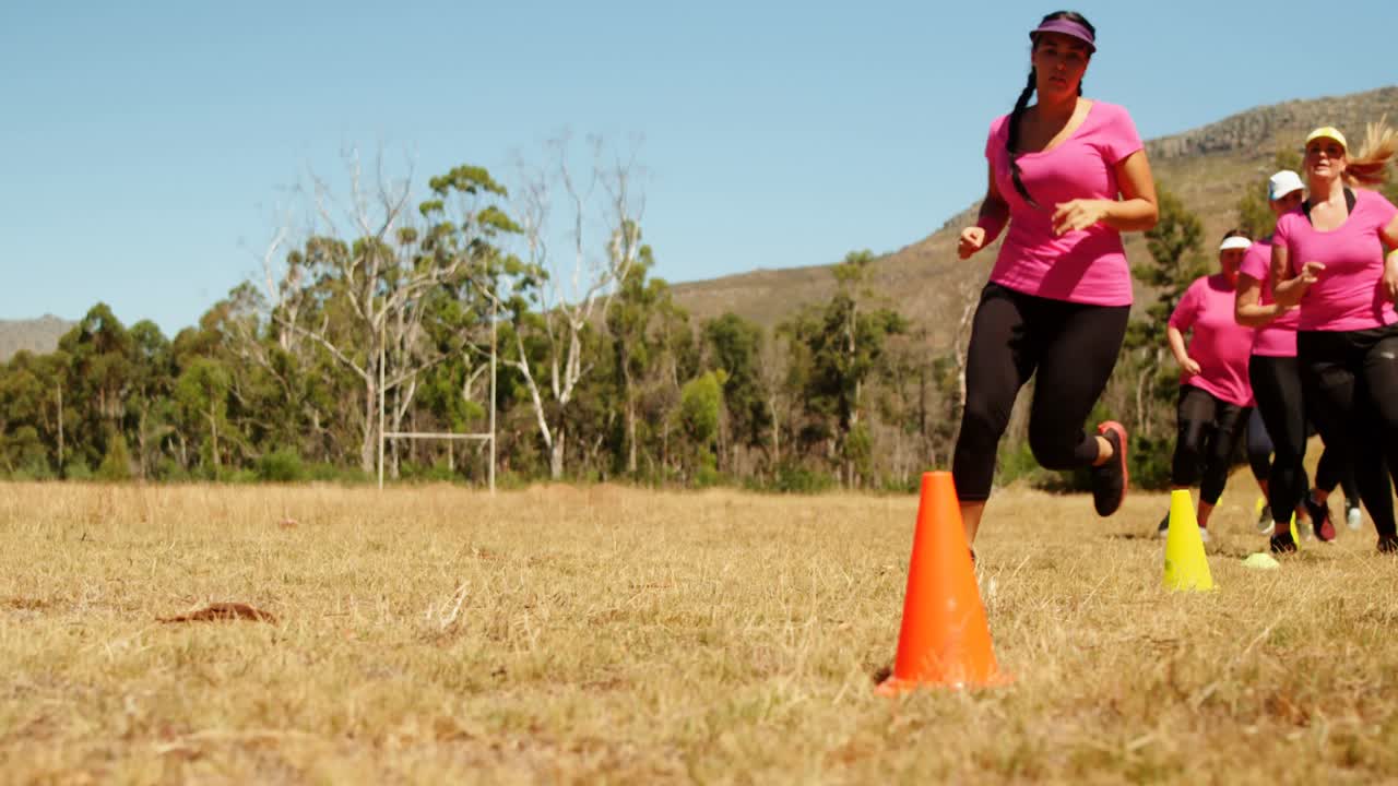 grupo de mujeres corriendo a través de conos en el campamento de entrenamiento