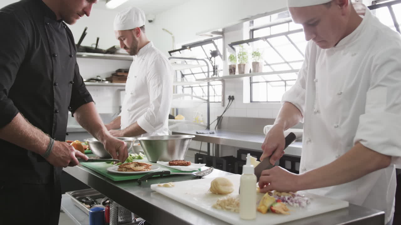 grupo de cocineros varones diversos enfocados preparando comidas en la cocina, en cámara lenta
