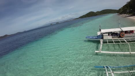 fpv drone flyover traditional tour boats on turquoise water shoreline in coron, philippines