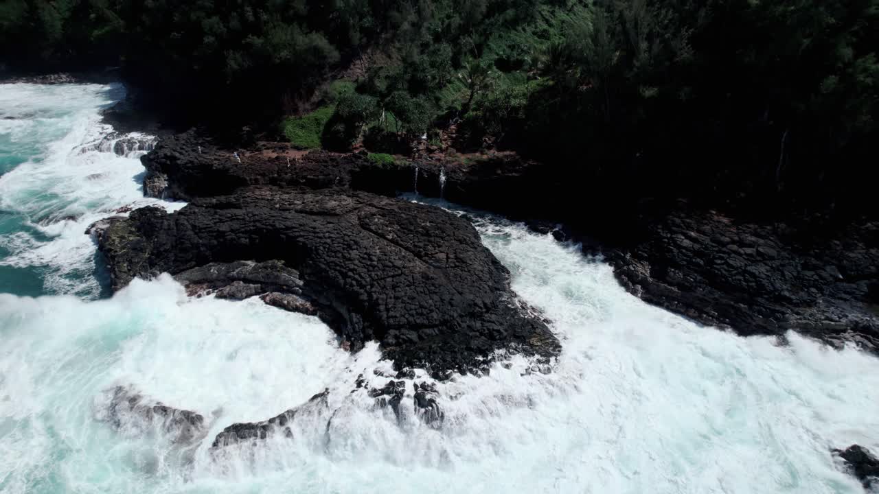 una ola masiva se estrella sobre la parte superior del baño de reinas en la rocosa costa norte de kauai, tirón aéreo