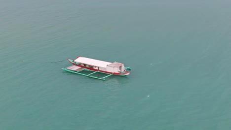 beautiful aerial view orbiting the fishing boat stop and floating in calm turquoise seawater not far away from the shore