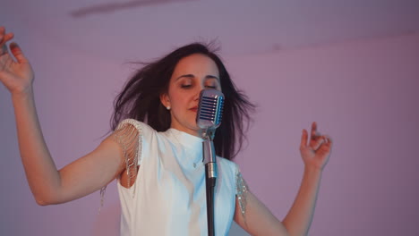 singer in a white gown passionately performing into a vintage microphone, with expressive hand movements and hair flicks, set against a soft white and pink background