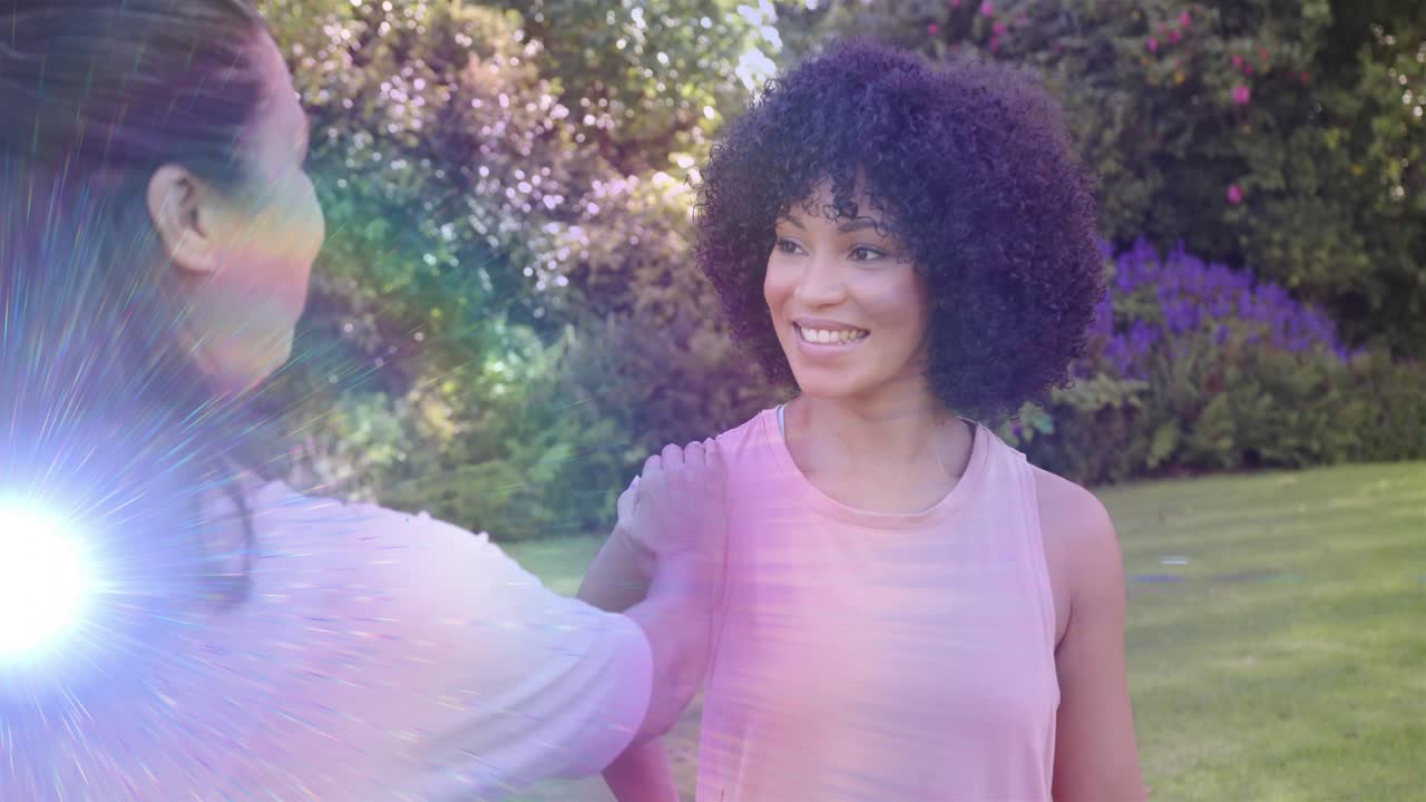 Left woman placing hand on shoulder, woman with curly hair smiling, greeting, lens flare aiding ads