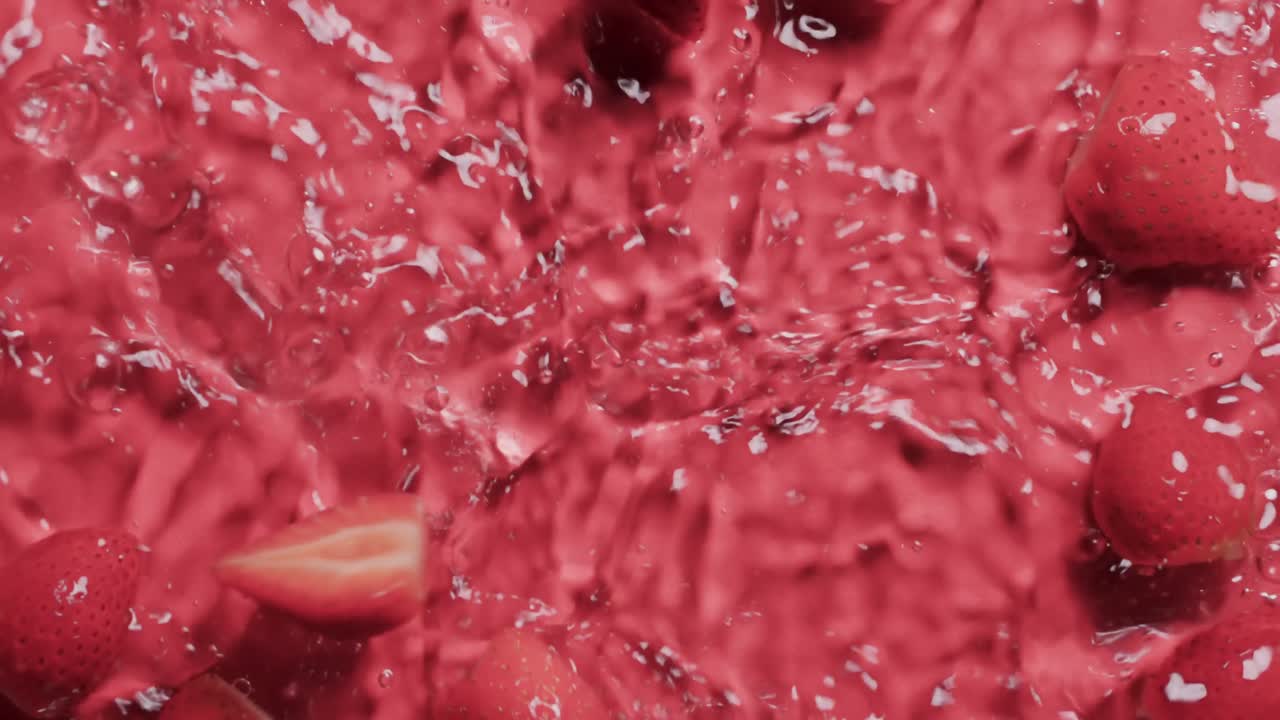 Video of strawberries falling into water with copy space on red background