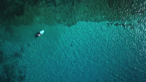 Luftbild-über-Einem-Boot,-Das-über-Einem-Korallenriff-In-Kristallklarem-Wasser-Verankert-Ist