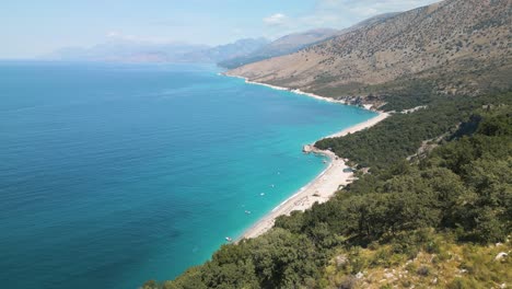 drone dolly push past rugged hillside to reveal tropical white sand party beach