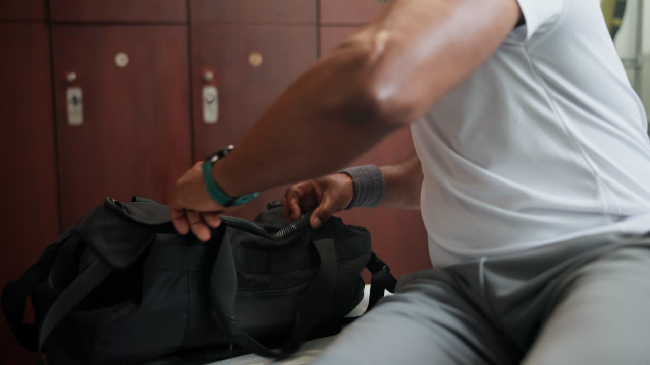 A person packing a sports bag in a locker room