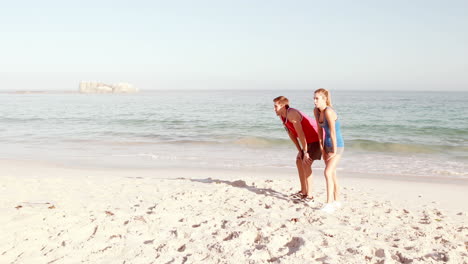 una pareja joven corriendo juntos en la playa.