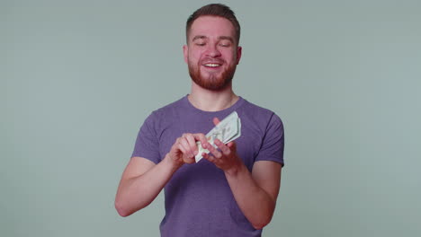 orgulloso arrogante rico hombre feliz sosteniendo dinero en efectivo en dólares billetes de banco, billetes de dólar cayendo alrededor