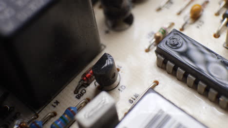 a transistor and ic integrated circuit chip on a dusty old board with many other electronic components