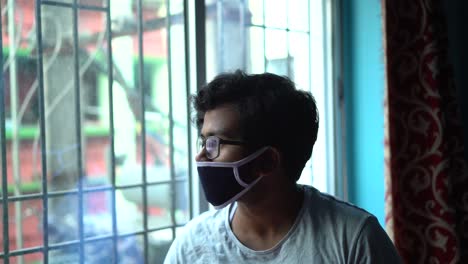 sad indian young male looks outside the window in his room in lockdown due to covid19 corona virus