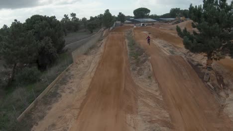 Antena-En-Cámara-Lenta-Del-Piloto-De-Motocross-Tomando-Aire-En-La-Pista-De-Tierra