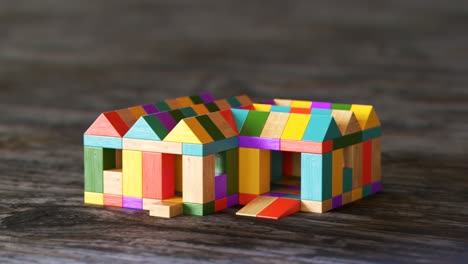 Colorful-house-being-build-from-a-pile-of-colorful-wooden-blocks.-Camera-position-pans-around-it.-Construction,-development-of-preschool-kid’s-building-imagination.-Fun-with-learning-aspects.