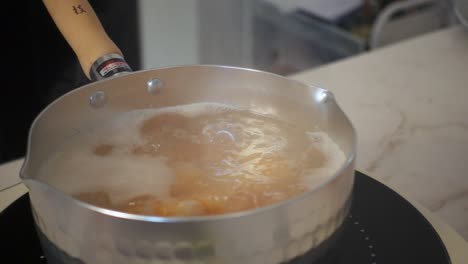 close-up of shrimp gently boiling in a hammered metal pot, with bubbling broth and steam rising in a softly lit kitchen environment.