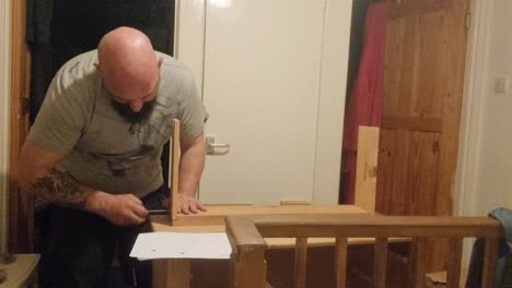 Caucasian-bearded-male-assembling-flat-pack-pine-furniture-screwing-together-board