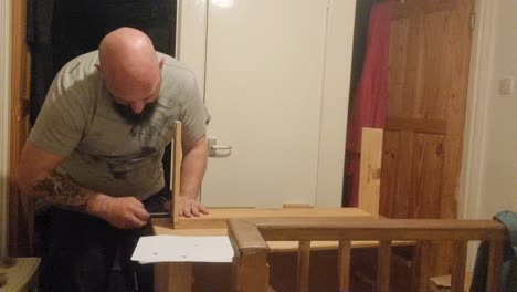 hombre caucásico barbudo ensamblando muebles de pino de paquete plano atornillando juntas la tabla