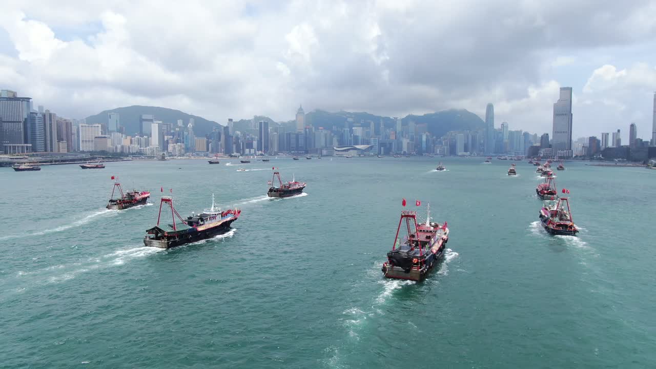 convoy de barcos de pesca locales que causan en la bahía victoria de hong kong, con el horizonte de la ciudad en el horizonte, vista aérea