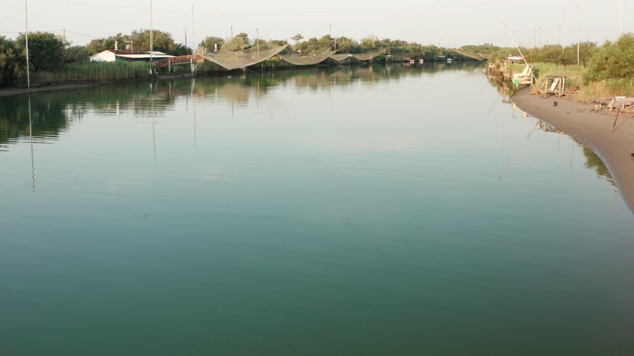 paisaje de cabañas de pesca en el río con la típica máquina de pesca italiana, llamada ""trabucco"",lido di dante, fiumi uniti ravenna cerca del valle de comacchio