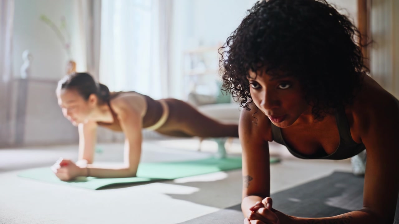 Women planking together home living room. Fitness partners core workout on mats.