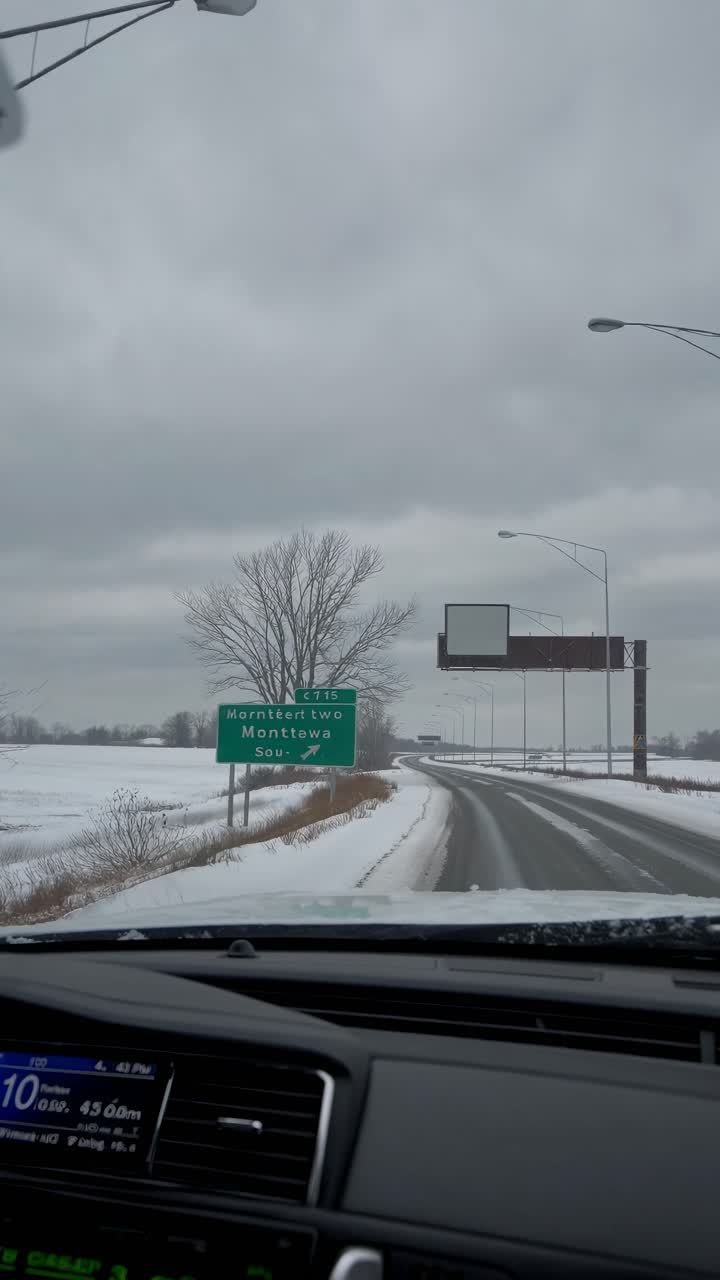 Video of a snowy road from a car's dashboard perspective, capturing a wintry landscape with overcast
