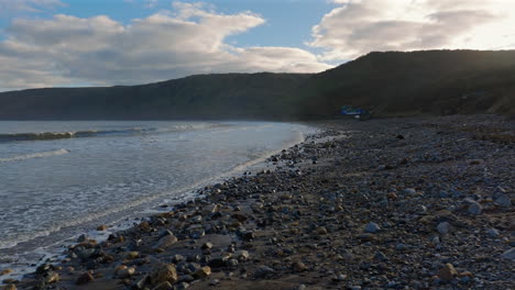 low drone shot over runswick bay pebble beach looking down the coast