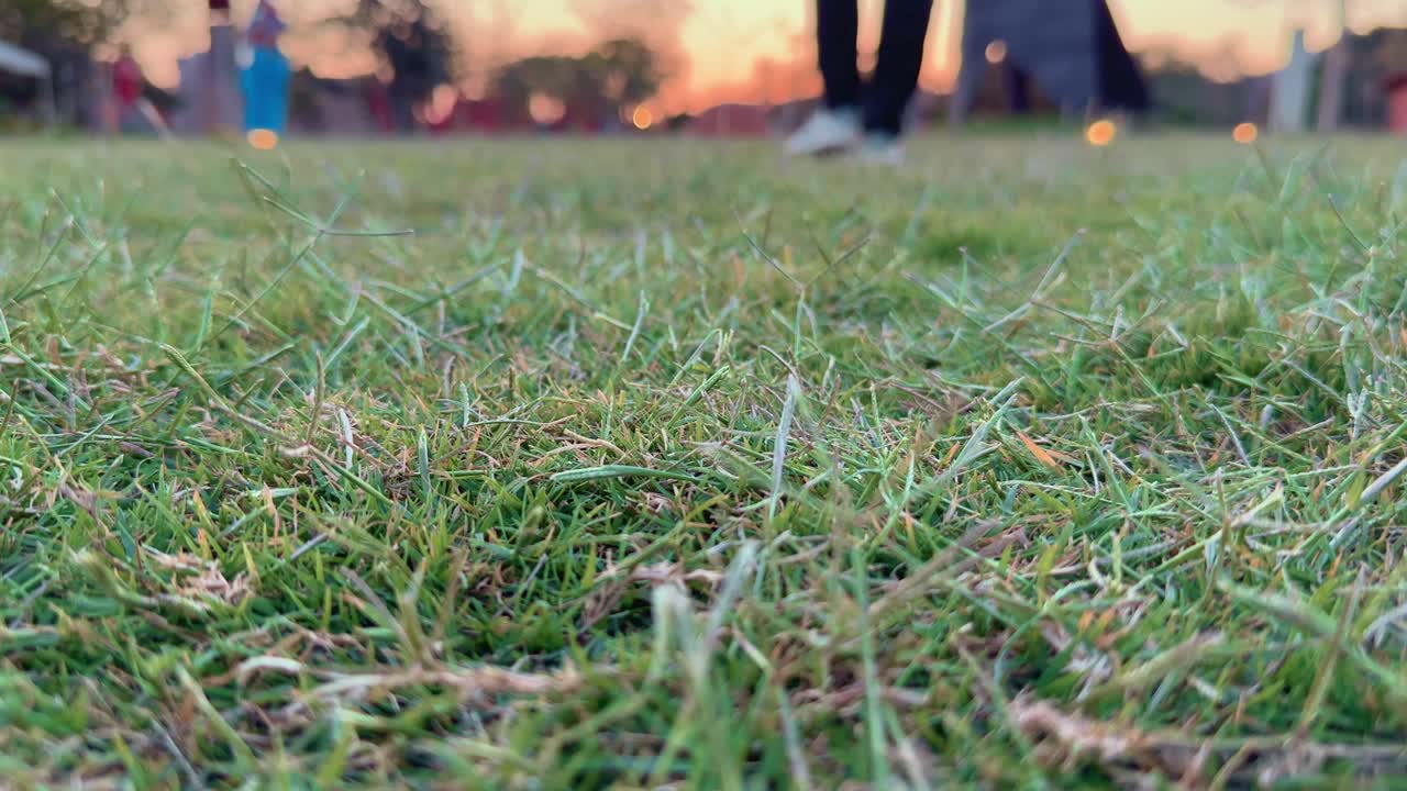 closeup of men's feet walking away from the camera on the green lawn grass