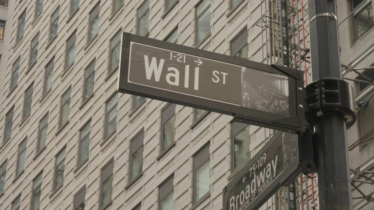 Nærbillede panorering af Wall Street og Broadway Street med bygning og stillads i baggrunden
