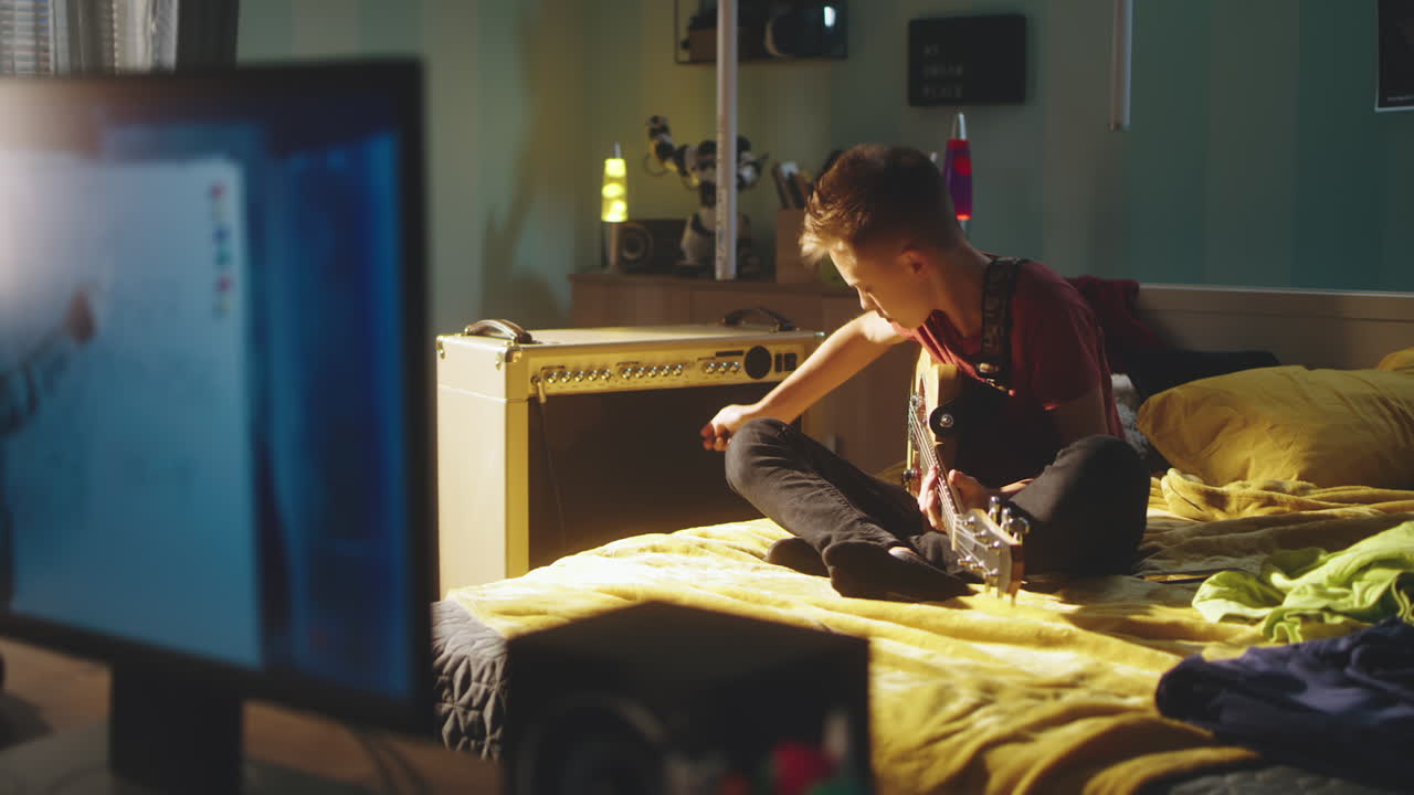 Teenage Boy Learning Guitar in Bedroom