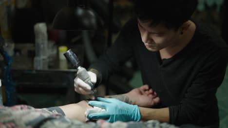 a tattoo artist working on a client's arm in a tattoo studio