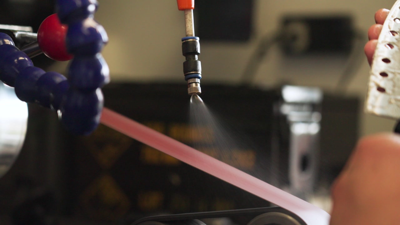 Slow motion close-up of knife sharpening with water cooling system in Malaysia, showing precision grinding, liquid spray, and industrial craftsmanship in detail. UHD.