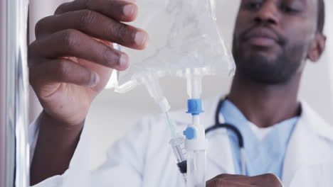 african american male doctor checking drip in hospital room, slow motion