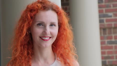 a cheerful woman with beautifully vibrant red hair captured in an enchanting portrait setting a cheerful young woman with beautiful curly red hair smiles brightly in an elegant outdoor location