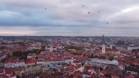 Vilnius-Old-Town-Aerial-Cityscape,-Tilt-Up-Revealing-Hot-Air-Balloons