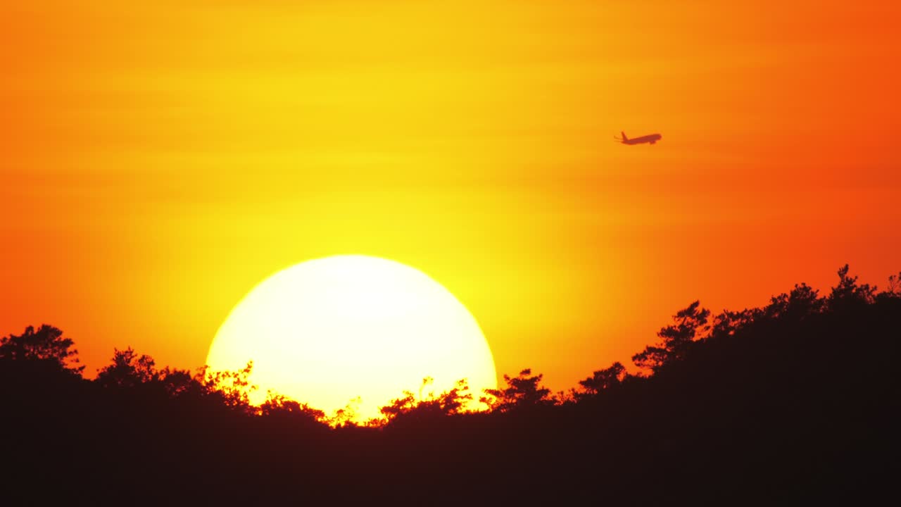 해가 지는 배경에서 지나가는 여객기,