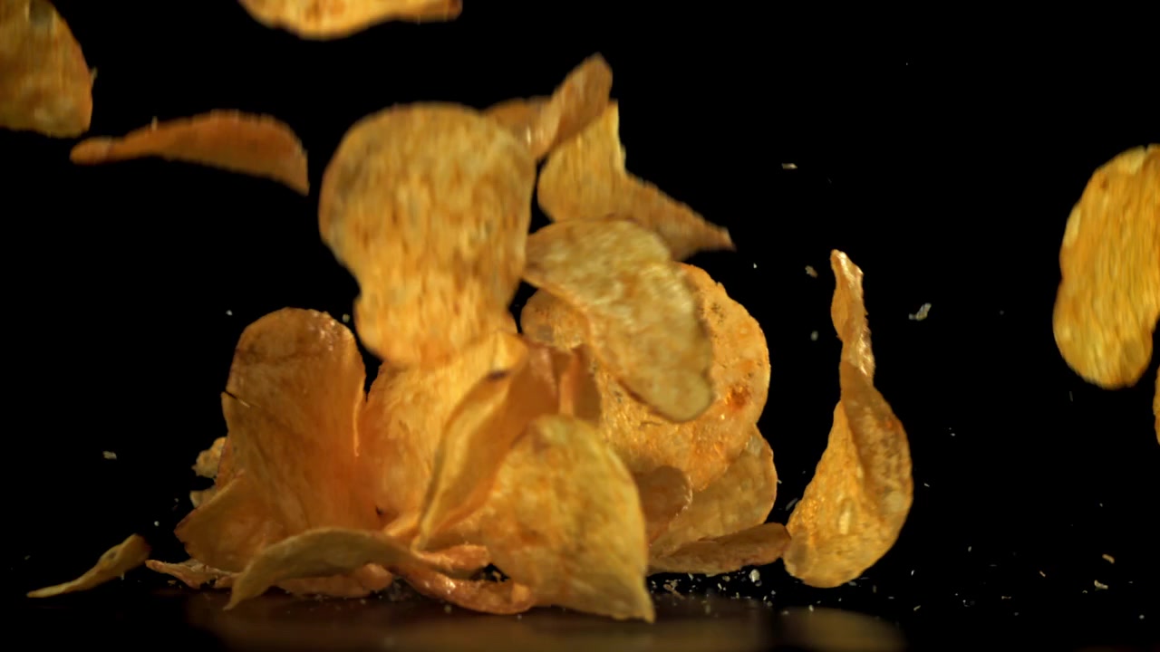 Crispy Potato Chips Falling in Slow Motion on Black Background