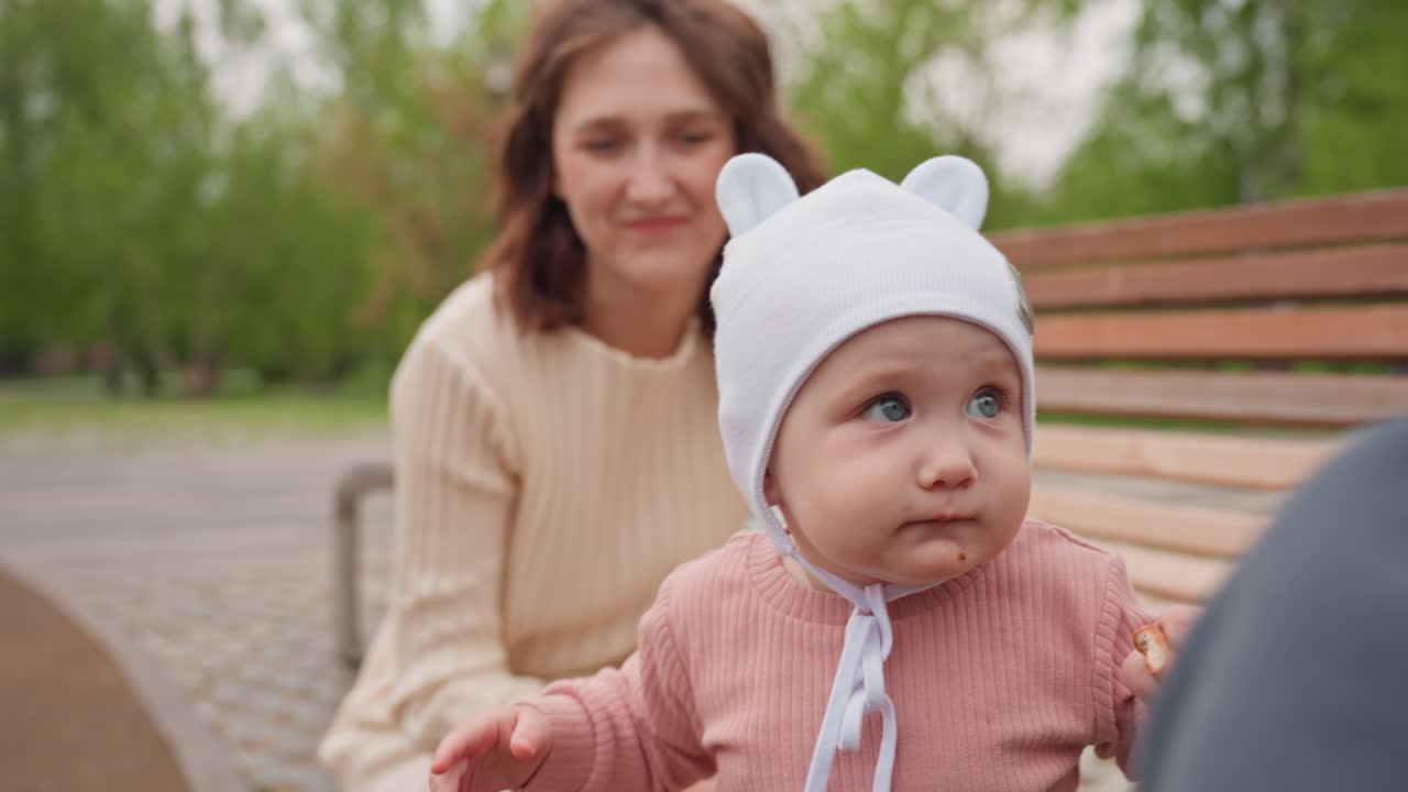 Mother And Baby Enjoying Sunlight, Happy Mother Bonding With Inquisitive Infant Outdoors, Mother Lovingly Interacts With Her Inquisitive Child Amid Bright Park Surroundings And Leafy Trees