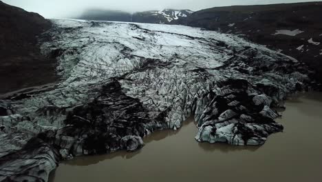 Aerial-panoramic-view-of-Sólheimajökull-glacier,-melting-into-water,-in-summer,-Iceland