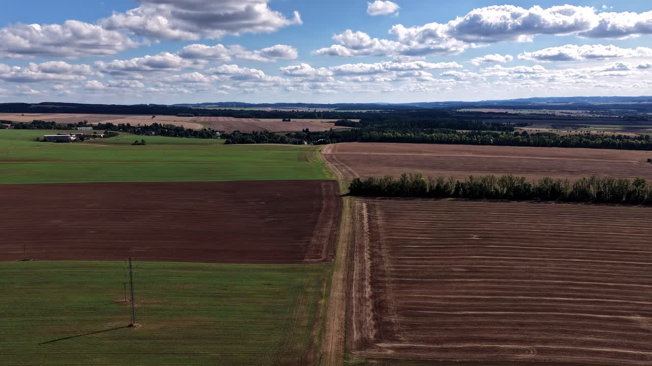 Hyperlapse of floating and dissolving clouds over a landscape of fields and meadows from a drone