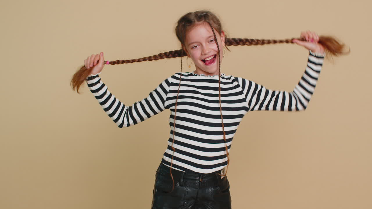 기쁜 웃긴 괴롭힘 어린 소녀는 혀를 보여 주고 어리석은 얼굴을 만들고 농담을 하고 조롱합니다.