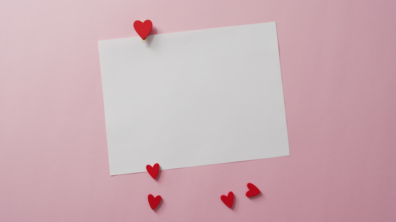 White card with copy space and red hearts on pink background at valentine's day