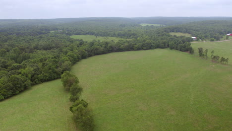 pull back over green pasture and trees in southern missouri on a cloudy summer day