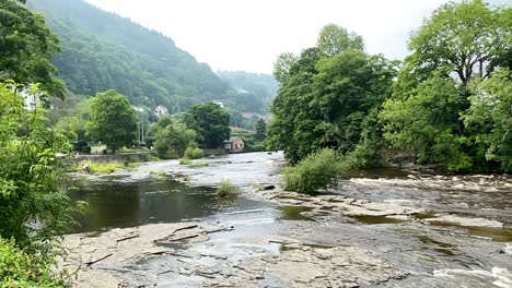 un hermoso video en cámara lenta del río dee fluyendo sobre el lecho rocoso en llangollen en una mañana de verano brumosa