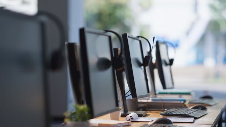 Empty call center office with headsets resting on computer monitors closeup