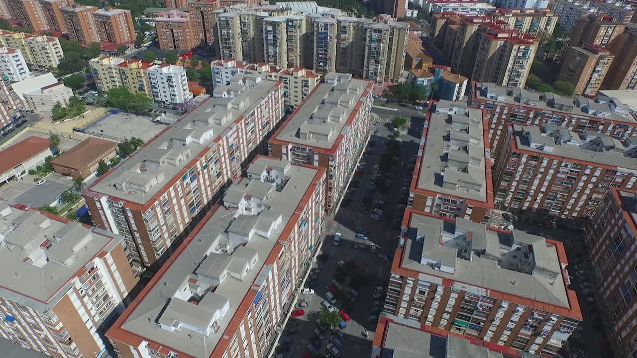 Un drone ruota sopra una grande rotatoria, poi si inclina verso il basso in una vista dall'alto dei tetti di Malaga