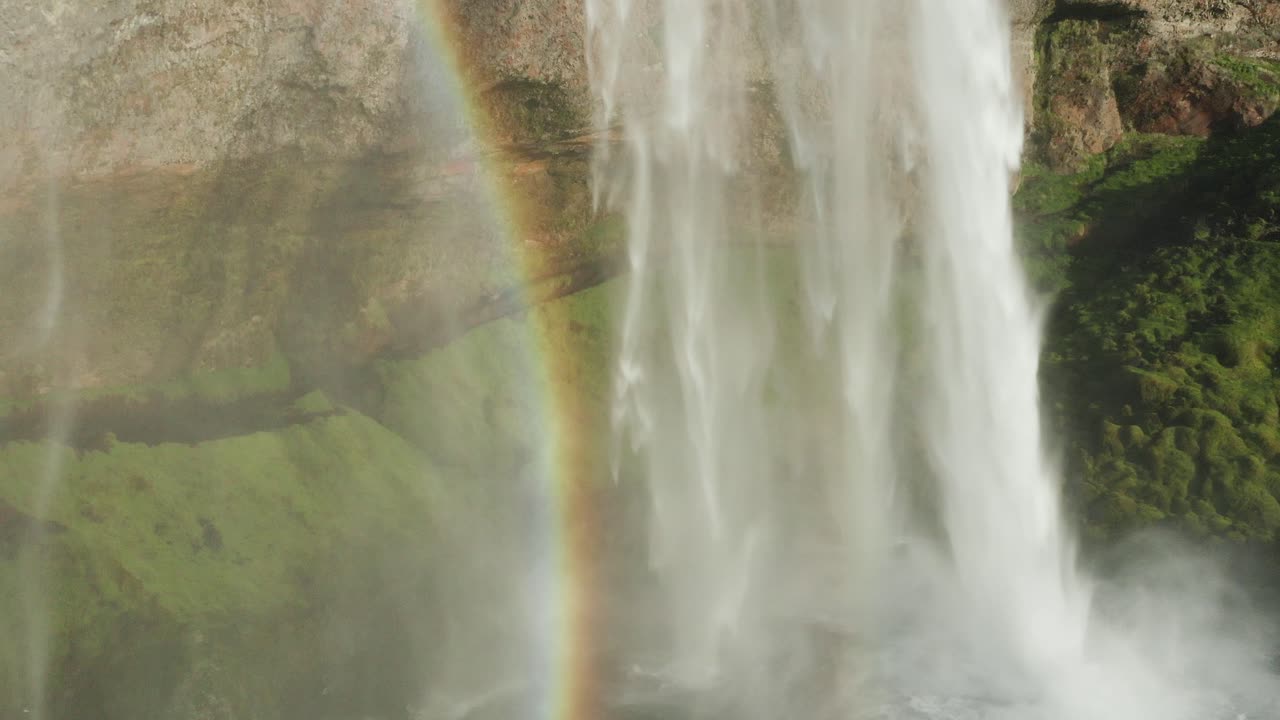 Flying past stairs at base viewpoint of Seljalandsfoss waterfall, rainbow