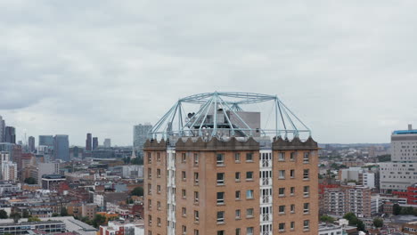 Fly-around-top-of-Winterton-House-towering-above-surrounding-development.-Modern-downtown-skyscrapers-moving-in-background.-London,-UK