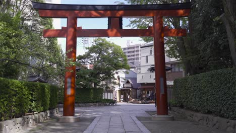 typical japanese red torii gate at entrance of nezu shrine in tokyo, japan with residential area in backdrop