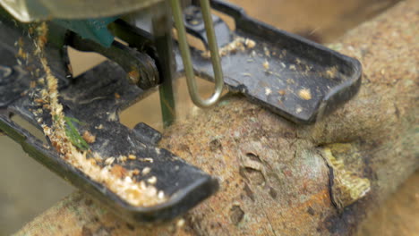 man sawing wood log using power jigsaw